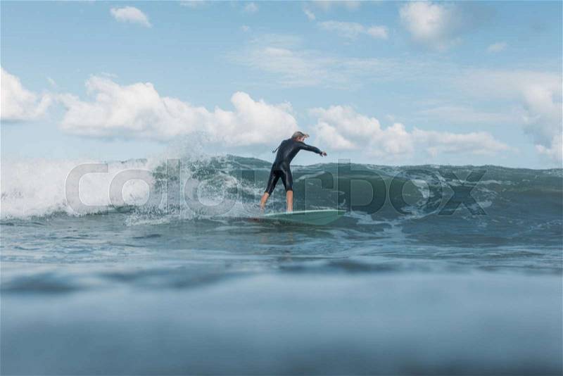 Male surfer riding wave on surf board in ocean , stock photo