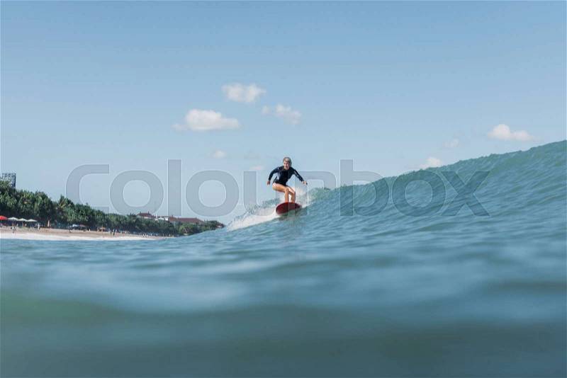 Female surfer riding wave on surf board in ocean, stock photo
