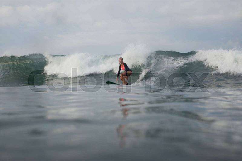 Woman riding wave on surf board in ocean, stock photo