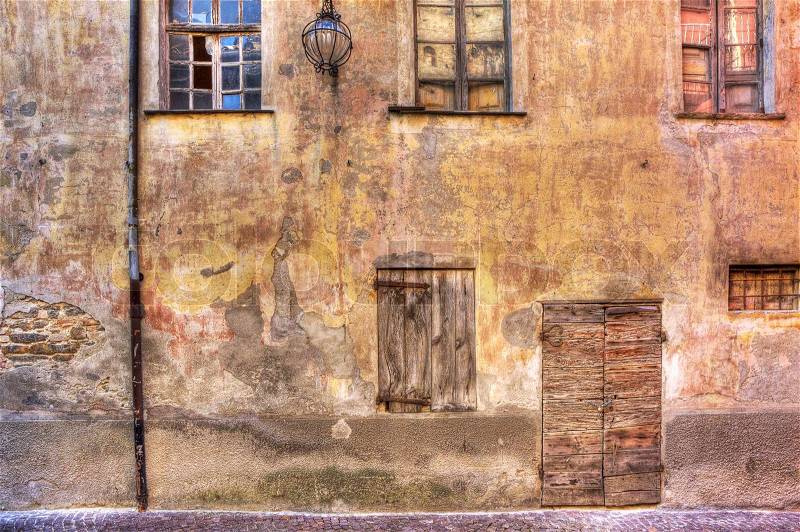 Old abandoned brick house with vintage wooden door and window in town of Serralunga D'Alba