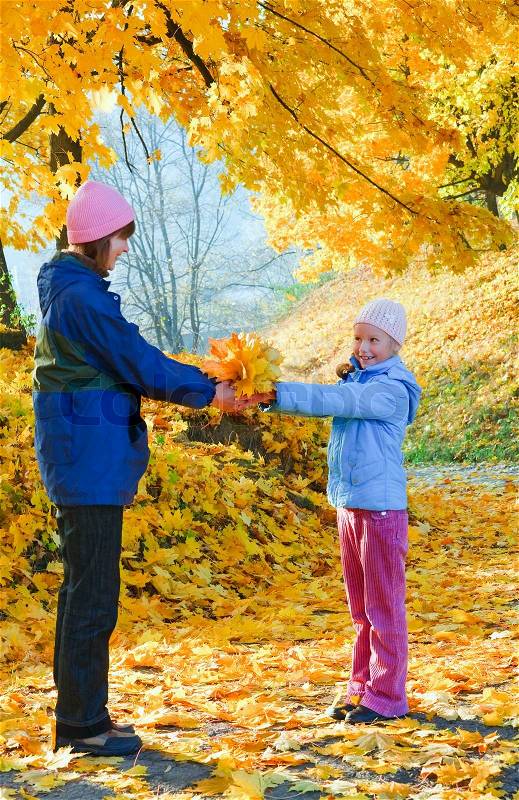 Happy family mother with daughter walking in golden maple autumn park, stock photo