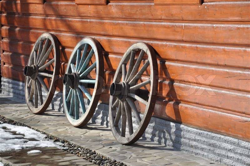 Wooden wheel lying infront of the wooden house, stock photo