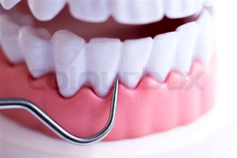 Dentist cleaning teeth with titanium metal tooth pick instrument to remove plaque and decay, stock photo
