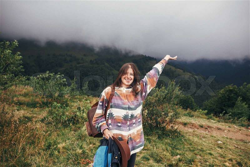 Happy traveler hipster girl raising hand in misty mountains. summer vacation. space for text. happy atmospheric moment. woman traveling. travel and wanderlust ..., stock photo