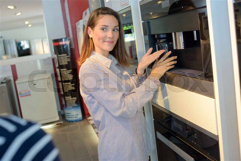 Shop worker presenting kitchen appliance, stock photo