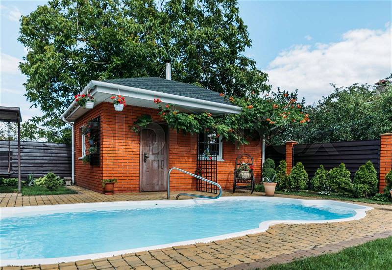 Wooden country house with swimming pool near by, trees and cloudy sky, stock photo