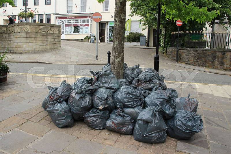 Many plastic grey waste bags around the trunk of the tree in the centre of the village Chepstow in Wales, stock photo