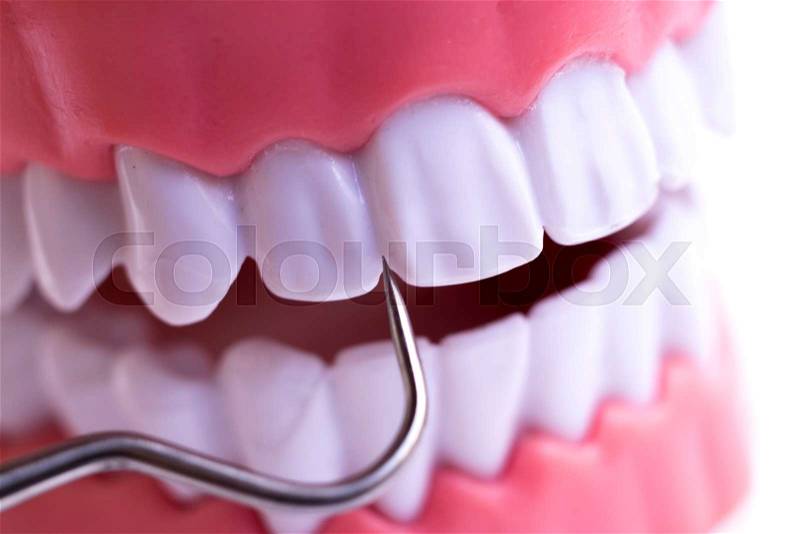 Dentist cleaning teeth with titanium metal tooth pick instrument to remove plaque and decay, stock photo