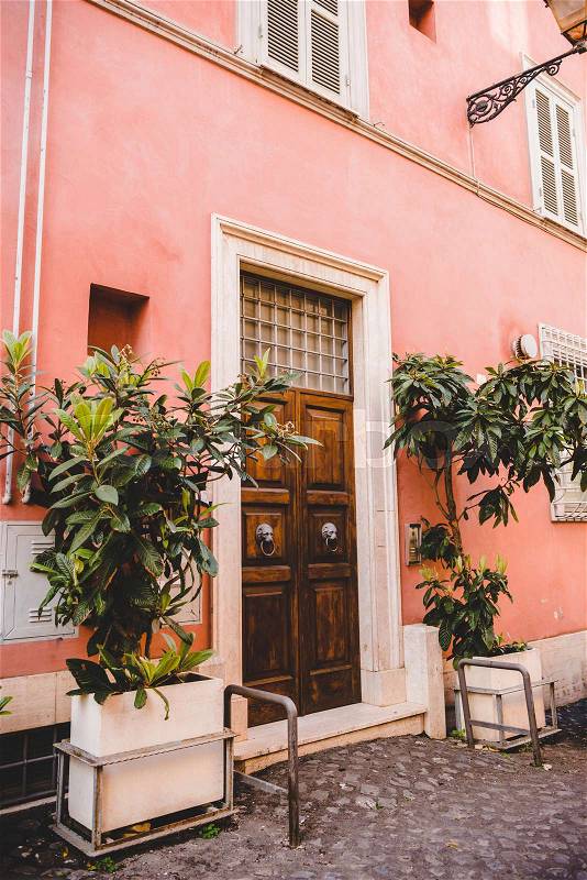 Pink building with potted plants on street in Rome, Italy, stock photo
