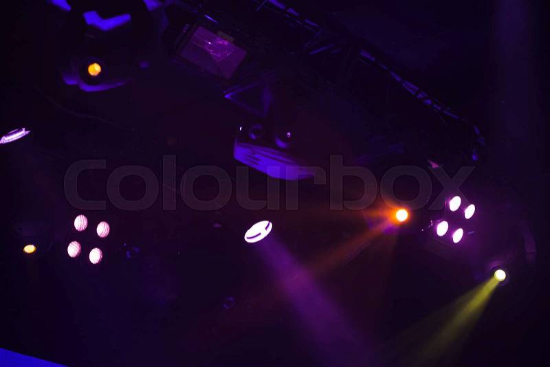 Scenic spot lights with strong beams in smoke over dark background, modern stage illumination equipment, stock photo