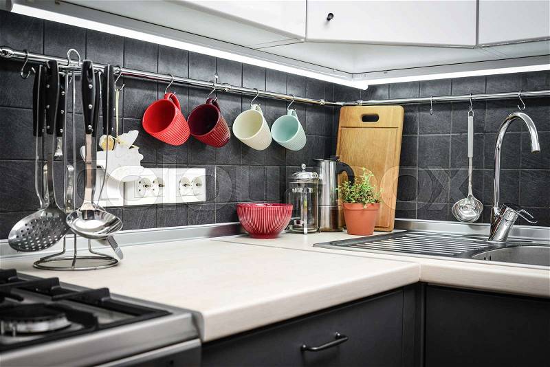 A fragment of the modern style kitchen with rail system and kitchen utensils and houseplant, stock photo