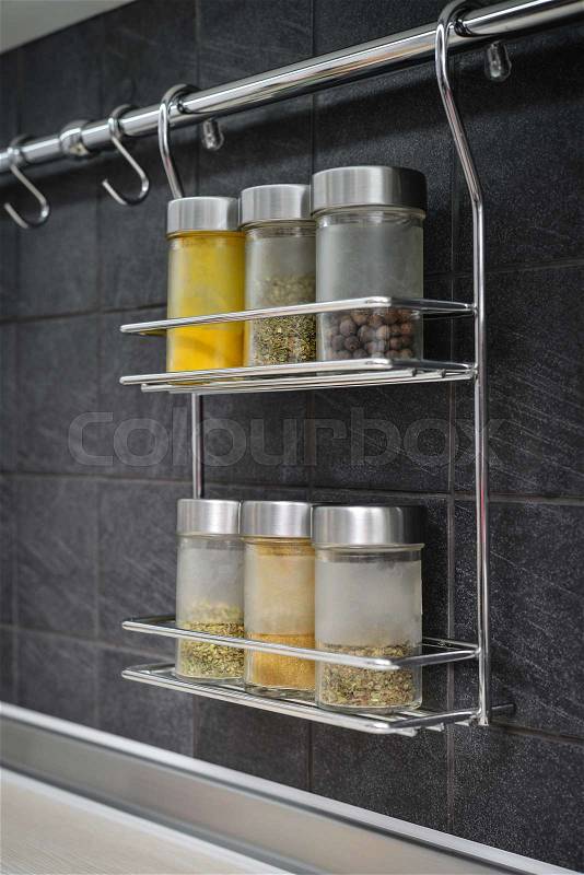 Jars of spices in hanging shelf in modern kitchen interior closeup, stock photo