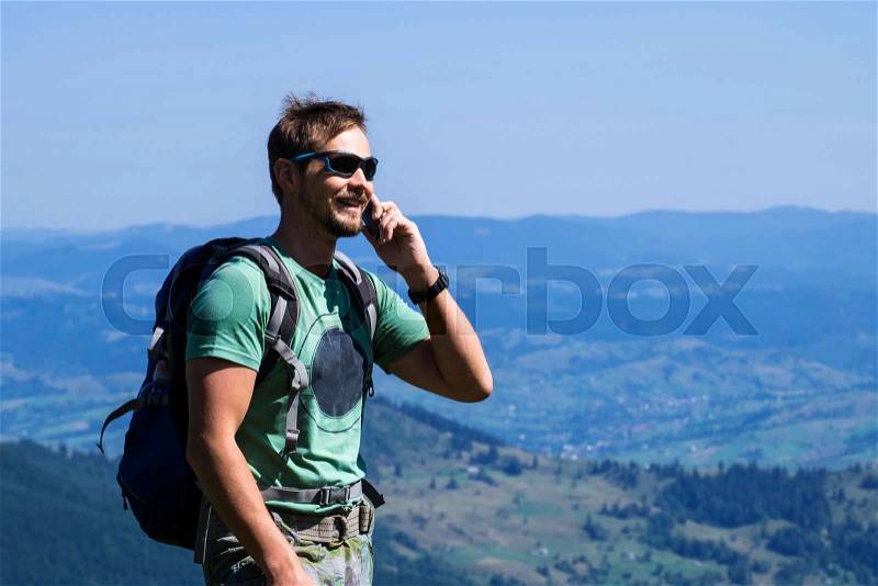 Man traveler speaks on the phone and laughs against the background of the mountains (Ukraine, Carpathians, Dragobrat), stock photo
