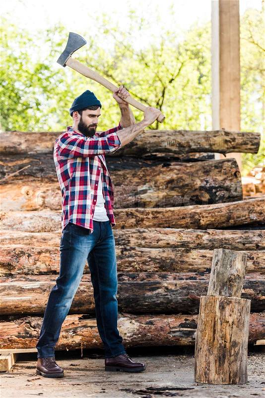 lumberjack in checkered shirt chopping log at sawmill , stock photo