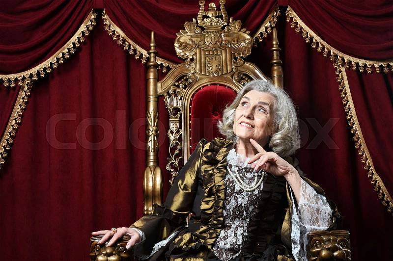 Beautiful senior woman Queen posing on throne, stock photo