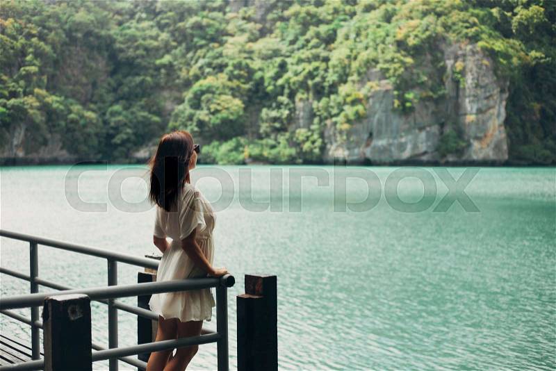 Side view of woman standing on pier near bay at Ang Thong National Park, Ko Samui, Thailand, stock photo