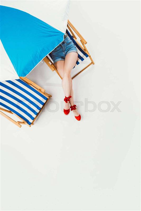 Top view of woman resting in chair under beach umbrella isolated on white, stock photo
