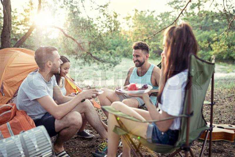 Party, camping of men and women group at forest. They relaxing and eating barbecue against green grass. The vacation, summer, adventure, lifestyle, picnic concept, stock photo