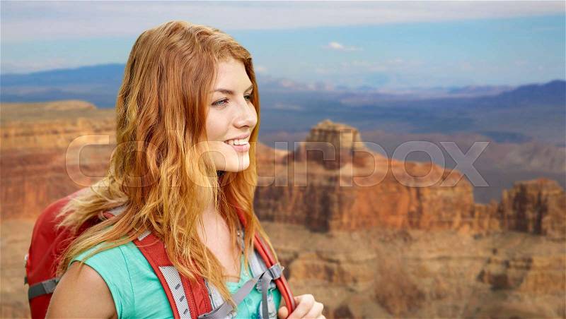 Adventure, travel, tourism, hike and people concept - smiling young woman with backpack over grand canyon national park background, stock photo