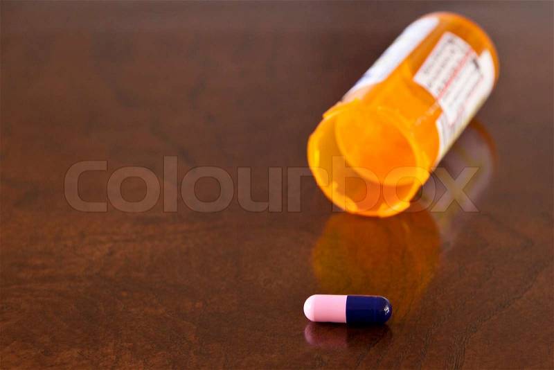 Last pill. One pill and orange bottle on a table, stock photo
