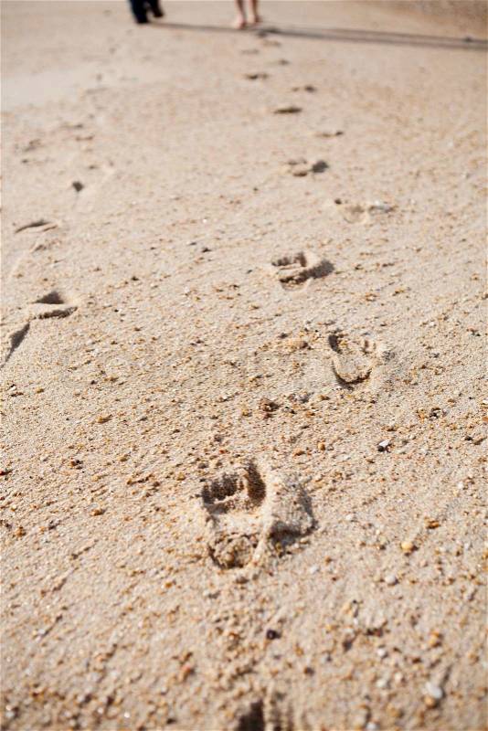 Close-up of footprints on sand, two people walking next to each other, stock photo