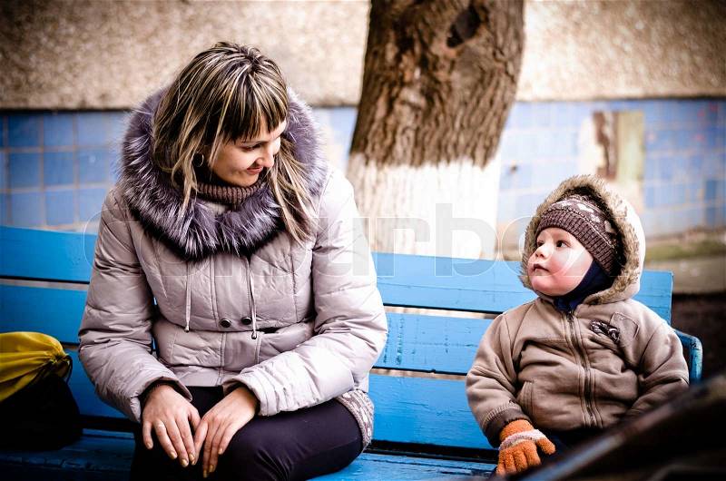 Mum and the son on a bench in a court yard, stock photo
