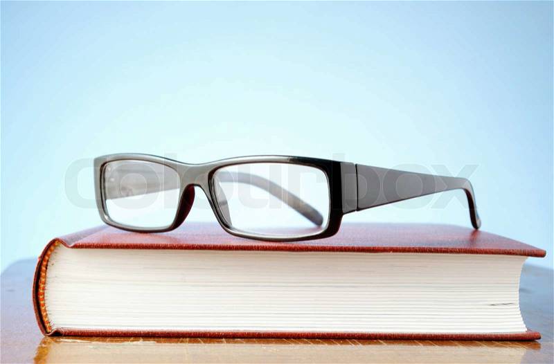 Black-rimmed glasses and a book on the table, stock photo
