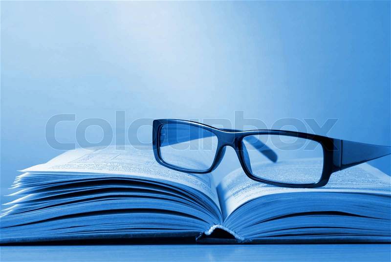 Black-rimmed glasses and a book on the table, stock photo