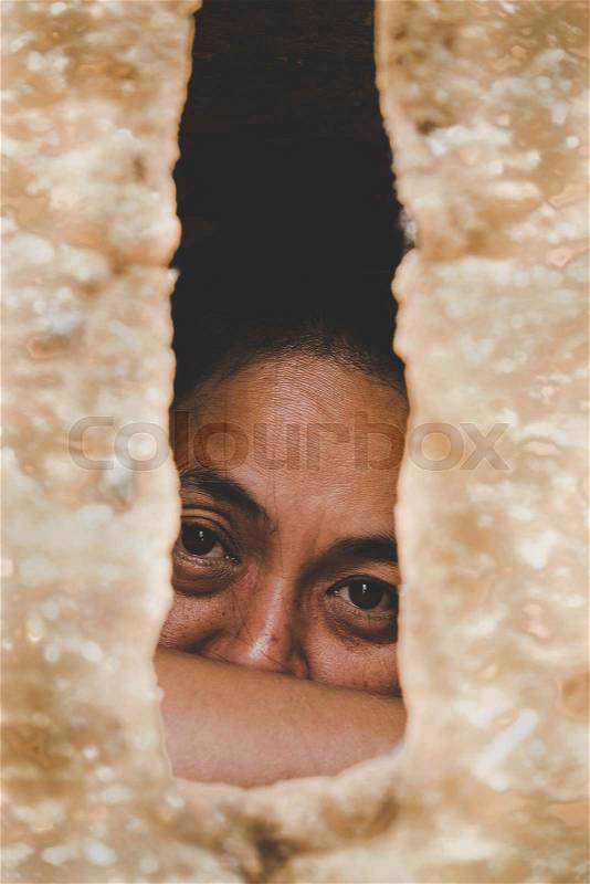 Woman looking from windows jail. trapped woman behind old clay house, stock photo