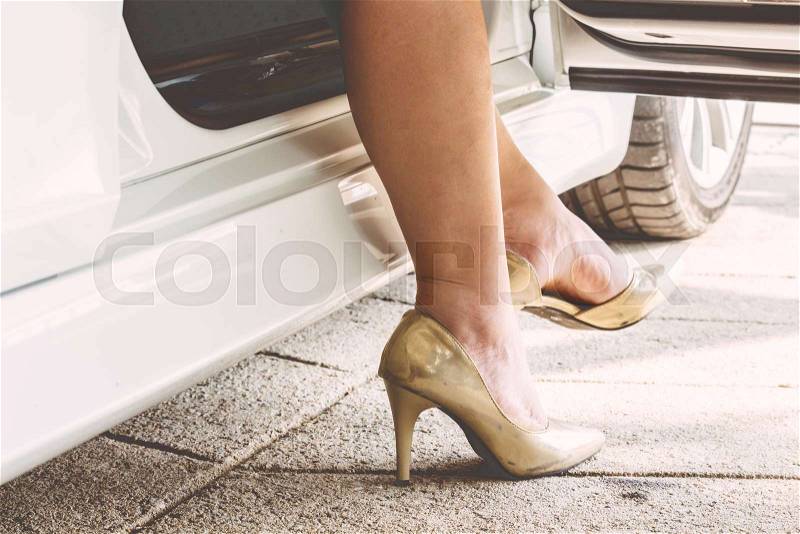 Female legs in tights and high heels in car outdoors, stock photo