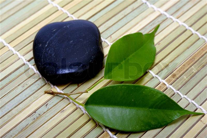 An image of a black stone for spa and green leaves, stock photo