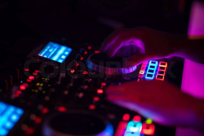 Dj mixes the track in the nightclub at party. DJ hands in motion, stock photo