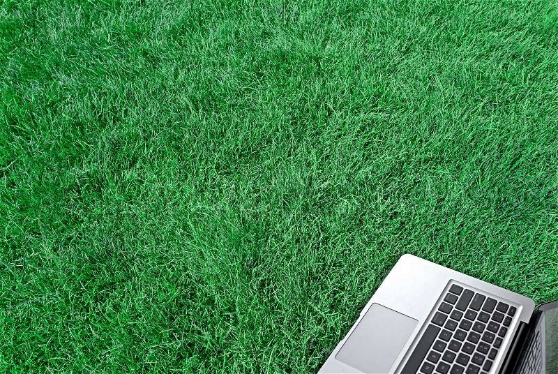 Laptop on the green grass texture, stock photo