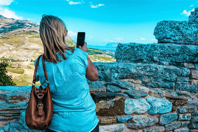 Woman taking photos of the scenery of Segesta at the Greek Theater in Sicily island, Italy, stock photo