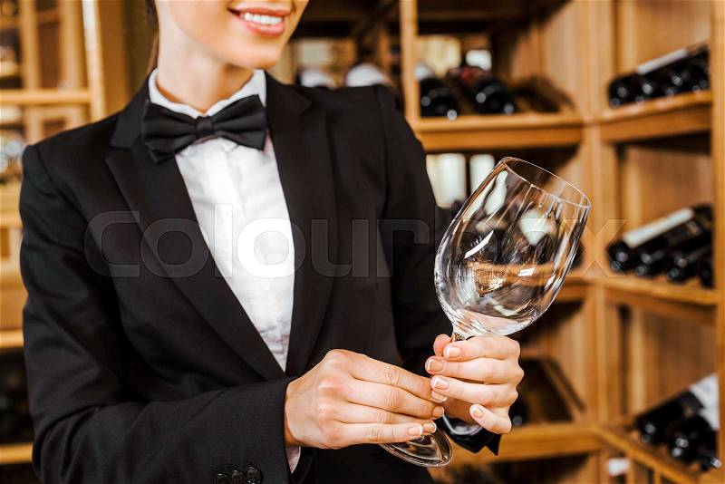 Cropped shot of female wine steward with clean glass at wine store, stock photo