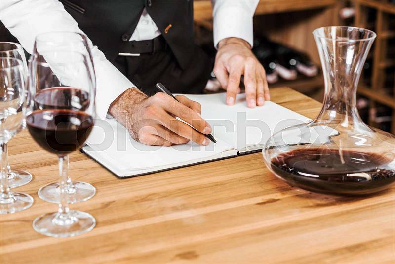 Cropped shot of wine steward making notes at wine store, stock photo