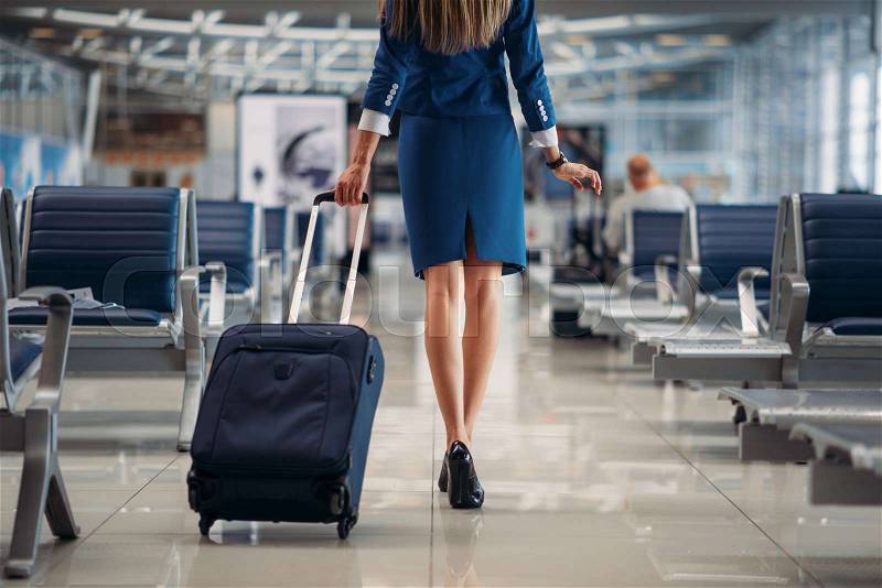 Air hostess with suitcase going between seat rows in airport. Stewardess with baggage, flight attendant with hand luggage, aviatransportations job, stock photo