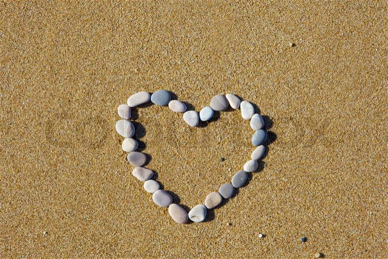 The heart is lined with stones on the sand, stock photo