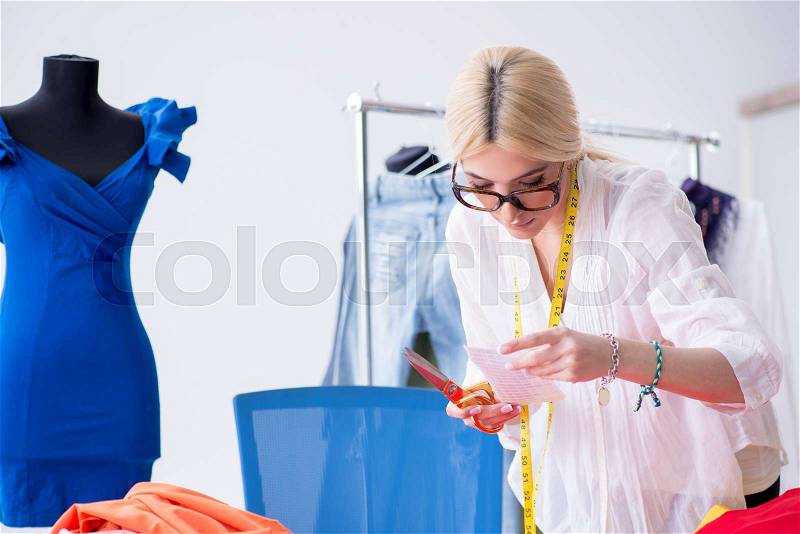 Woman tailor working on new dress designs, stock photo