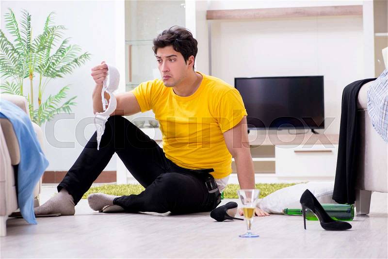 Man with mess at home after house party, stock photo