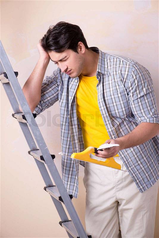 Young man applying plaster on wall at home, stock photo