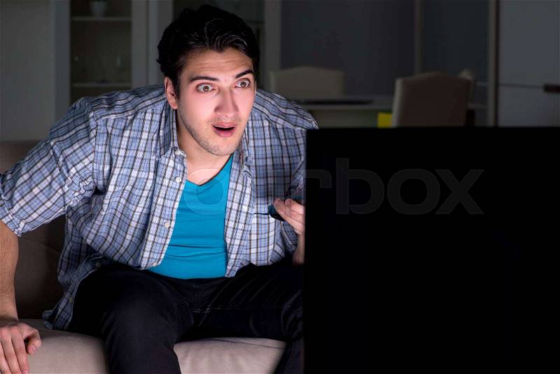 Young man watching tv late at night, stock photo