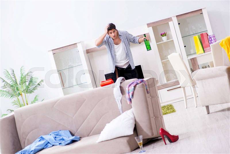 Man with mess at home after house party, stock photo