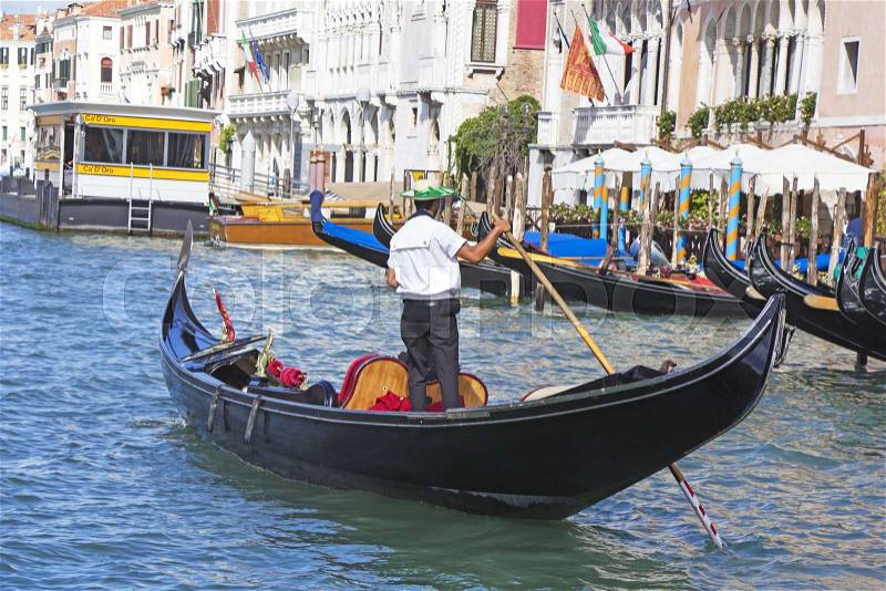Venetian gondolier in the gondola is transported tourists through canal waters of Venice Italy, stock photo