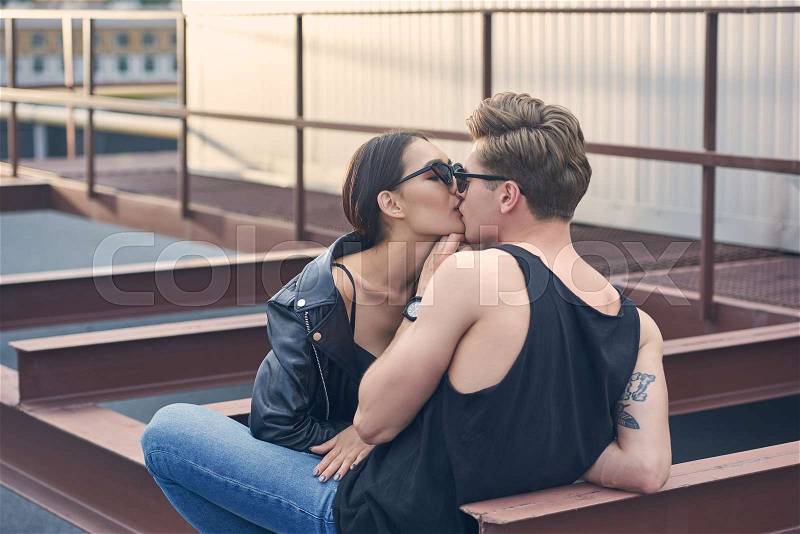 Interracial stylish hot couple kissing on urban roof, stock photo