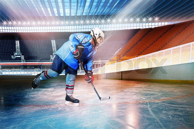 Side-view portrait of hockey player preparing to pass the puck during the game at ice stadium, stock photo