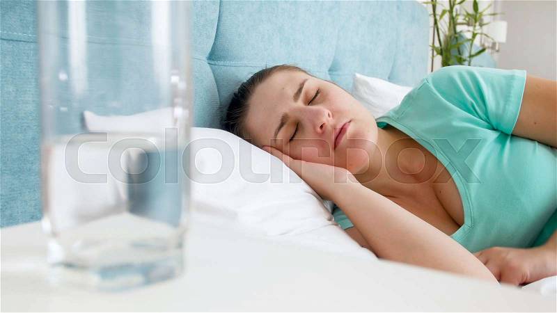Portrait of young woman wearing blue t-shirt sleeping in bed, stock photo