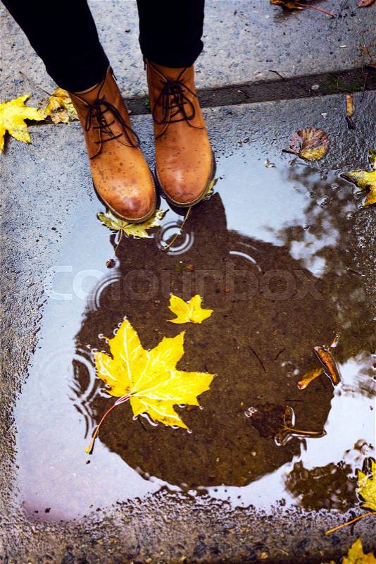 Girls leather boots at the puddle at the rainy autumn day, stock photo
