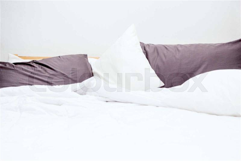 Messy bed and white bedding sheets and pillow, stock photo
