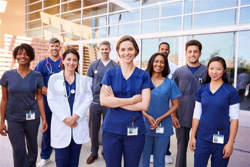Team of healthcare workers with ID badges outside hospital, stock photo